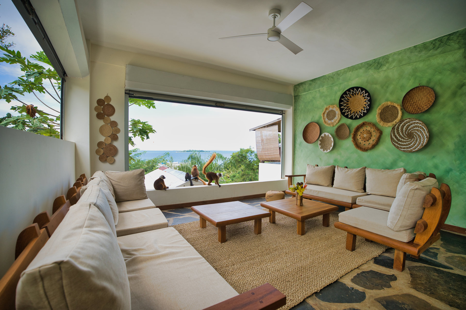 Open-plan lobby lounge with lemurs on the windowsill and ocean views beyond
